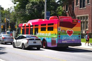 Stopped bus side reads "Love Drive Us All" 